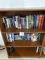 Wooden bookshelf with assorted books on shelves, front view showing overall condition and quantity.
