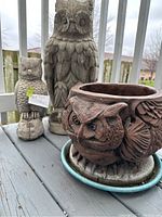 Photo showing the large and small owl statues along with owl-shaped planter from a side view on outdoor deck.