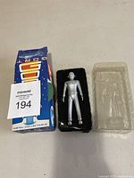 Silver metal Gort robot figurine in black plastic tray with original box beside it.