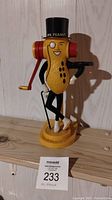 Front view of the Mr. Peanut figurine showing details of the face, top hat, crank, and base.