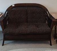 Front view of woven wicker loveseat with zebra print cushions showing full piece.