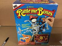 Photo of front of box showing game title and large motorized skeleton game piece standing on a platform with steering wheel and attached chests.
