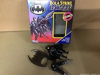 Main display of Batman Bola Strike box with figure and weapon outside box