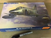 View of the full model kit box cover showing the RF-4E Phantom II aircraft illustration and the sealed condition with a Sharpie pen for scale reference.
