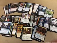 Photo shows a spread of over 100 Magic the Gathering cards in various colors and types, displayed on a flat surface.