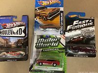 Photo showing four Hot Wheels diecast cars in sealed original packaging on cards.
