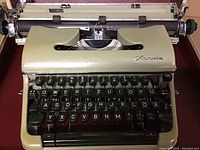 Front view of the lime-green Olympia typewriter showing black keys and chrome logo on body.