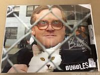 Full view of hand-signed Bubbles photo including the white cat and clear signature in silver ink, a Sharpie marker is present for size reference.
