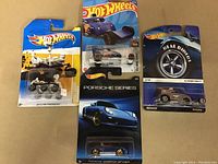Four Hot Wheels diecast cars in original sealed packaging shown front view. Cards include variety of series and designs.