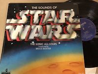 Front cover of 'The Sounds of Star Wars' LP showing metallic logo and desert scene with vinyl partially visible.