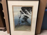 Full front view of framed artwork showing black frame, white mat and print of two stylized trees