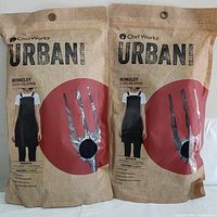 Two sealed aprons in packaging showing quantity and brand