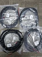 Four new MIG MAG welding machine flow hoses sealed in original clear plastic bags laid out on a textured fabric surface.