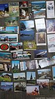 Multiple vintage postcards laid out on the floor showing a variety of North American scenes including buildings, landscapes, and historical images.