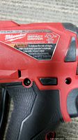 Close-up of Milwaukee Fuel Impact Driver label showing model JTAF12G01 and safety warning.