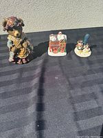 Photo showing all three items: bear lady figurine, Christmas house, and snowman with shovel.