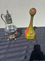 Wide view of Italian leather cork decanter and metal-accented glass coffee carafe with stand.