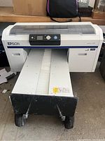 Front view of printer with conveyor tray and wheeled base