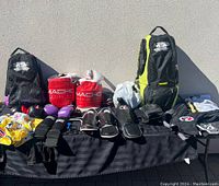 Full view of kids martial arts gear spread on a table including bags, gloves, pads, helmet, and clothing.
