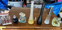 Seven various perfume bottles in different styles and colors on a wooden surface.