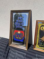 Full view of the framed Molson Canadian bar mirror leaning against a wall outdoor.