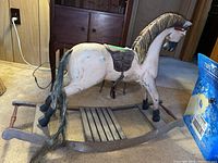 Full side view of carved wood rocking horse on curved rockers showing saddle, tail and footrest