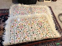 Full view of folded embroidered felted wool blanket showing the floral embroidery and fringe edges.