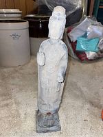 Full frontal view of concrete standing Buddha statue on a square pedestal base.