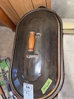 Photo of the metal lid with wooden handle on top of the copper wood bin showing size label and lot number sticker.