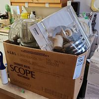 Box containing multiple Cuisinart food processor parts including blades and discs inside a clear plastic holder.