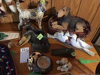 Overview photo of dog figurines including cast iron dogs, ceramic dog candle holder, and Sandicast terrier figurine in basket