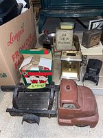 Front view of rusty vintage metal toy pickup truck, Rex Mixture tin container, clock, and several small tins and items.