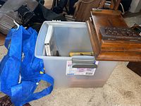 Plastic bin containing book and cards highlighted next to blue tote
