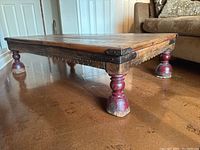 Side view showing the turned red legs, iron corner brackets, and wood surface