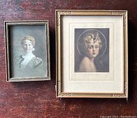 Pair of framed items on wooden surface: colored photographic portrait and 'Light of the World' print.