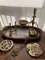 Photo of entire brass tea and candle set on woven tray, showing kettle, candle holders, two trivets, and strainer