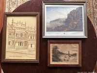 Lot of 3 framed artwork pieces displayed on round wood table, showing overall items and sizes