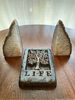 Top view of two natural geode book ends surrounding a metal wall hanging plaque with tree of life design and word 'LIFE'.