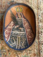 Full view of the oval wooden bowl showing the hand painted religious figure inside with crown and palm leaf.