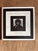 Photograph of the front cover of the book showing a black and white photo of a man with afro. The book title is 'Linda McCartney's Sixties Portraits of an Era'.