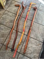 Four canes arranged on a tiled floor showing various natural and dark wood finishes, different shapes and sizes.