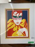 Front view of framed colorful print showing the full artwork, matting, and frame, with visible light reflections.