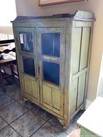 Full angle view of green painted wooden cupboard showing front and side panels