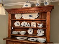 Wooden hutch displaying entire Royal Copenhagen set with multiple plates, bowls, serving pieces.