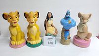 Five South Asian Disney character collectible Soaky bubble bath bottles arranged in a row on a white surface. From left to right: two Simba figures with yellow bases, Pocahontas in the center, Genie in blue, and Nala on a pink base.