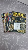 Image of 11 Gold Prospector magazines stacked and fanned showing varied colorful covers with mining and gold themes.
