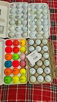 Photo shows 6 dozen used golf balls in four cartons, some white and some neon colors, with different branding and wear.