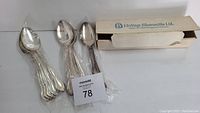 Lot of 14 silver spoons in Legacy pattern by Holmes & Edwards shown in unopened packaging and loose to display the design.