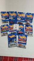 Full lot of 10 Hot Wheels cars in original blue packaging displayed on white surface.