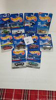 Lot of 10 Hot Wheels diecast cars in original Mattel blue packaging, unopened, arranged on a white surface.